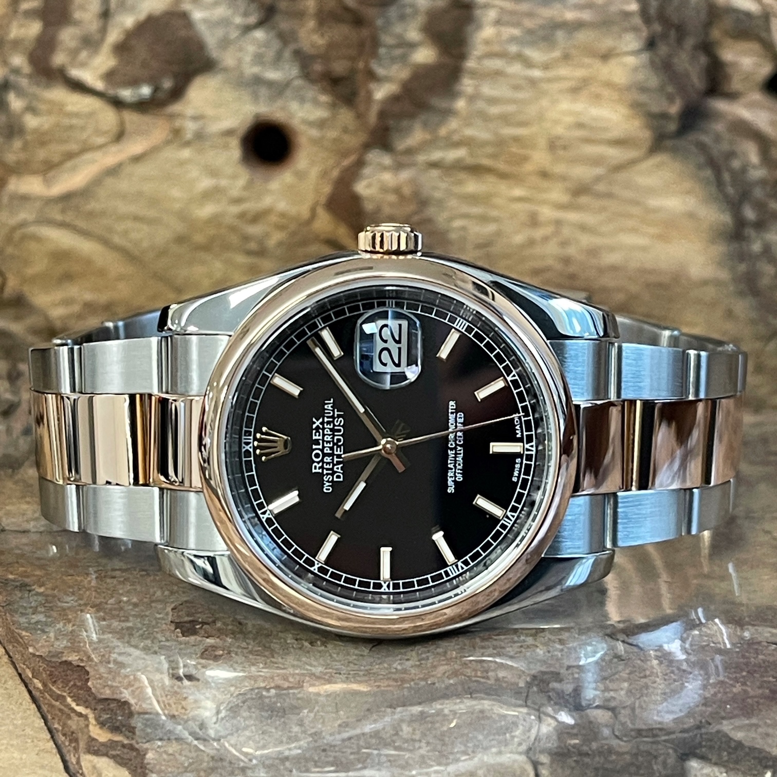 Gebrauchte Rolex Datejust 36 Ref. 116201 in Stahl/Roségold, in sehr gutem Zustand – liegende Gesamtansicht mit schwarzem Zifferblatt